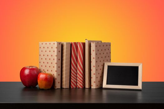 Education concept with stack of books on a table against colored background, front view