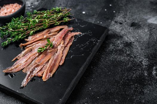 Anchovies fish fillet in Olive Oil. Black background. Top view. Copy space.