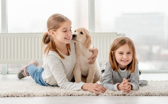 Happy friends and young golden retriever lying on floor in light room