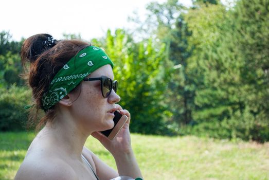 Serious stressed girl speaking on cellphone in park. Frowning young woman in casual calling on mobile phone, listening and staring into distance. Serious phone talk concept.