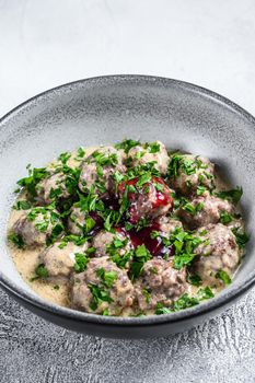 Ground beef meatballs with cream sauce on a plate. White wooden background. Top view.