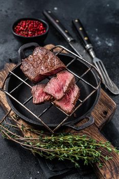 Grilled fillet mignon beef steak on a grill. Black background. Top view.