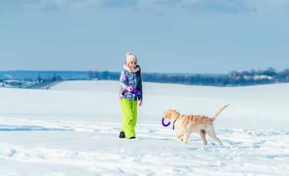 Happy girl running with cute dog in sparkling snow