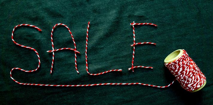 Sale, discount word made of red thread with a spool on a black background. Background, holiday concept. Black Friday - International Day of Shopping, Promotions, Discounts, Sales. Sales season is the fourth Thursday of November. Copy space, place for text, flat lay.