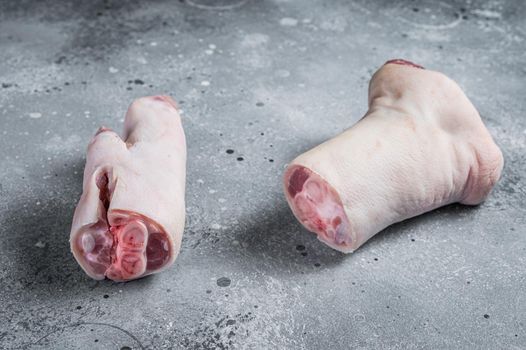 Raw pork hoof, feet, trotters on a butcher board. Gray background. Top view.