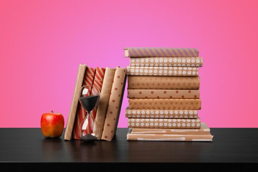 Education concept with stack of books on a table against colored background, front view