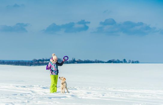 Cute girl playing with adorable dog on snowy field