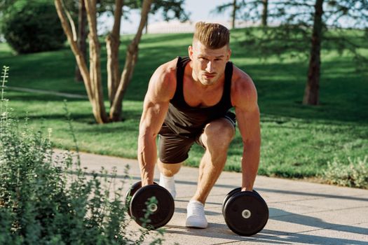 athletic man with dumbbells workout outdoors motivation. High quality photo