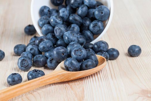 ripe blueberries, lying on a table and in a wooden spoon, closeup in the spring