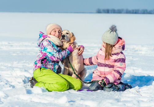 Cheerful girls with cute dog on winter walk