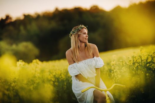 a woman enjoys a bike ride in a field full of bright yellow rapeseed.