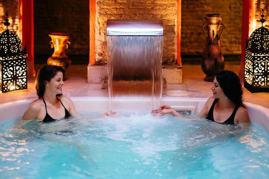 Two women enjoying Arabic baths Hammam in Granada, Andalusia, Spain. Elvira baths. Hot water pool.