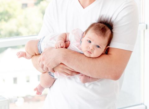 Baby protected by father's hands indoors