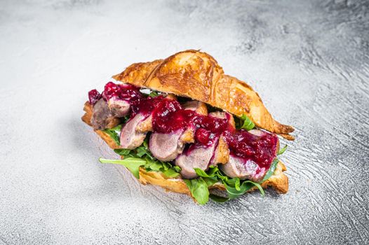 Duck breast Croissant sandwich with steak slices, arugula and sauce. White background. Top View.