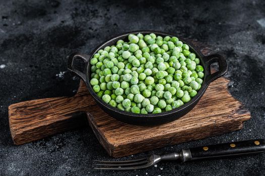 Fresh Frozen green peas in a pan. Black background. Top view.