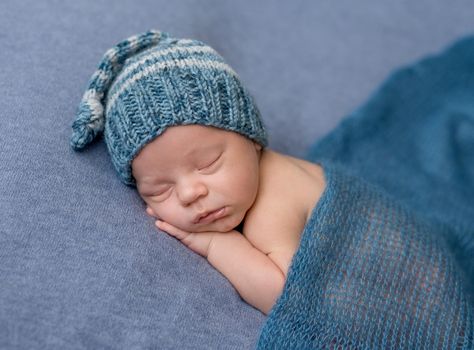 portrait of sweet sleeping newborn baby in hat covered with blanket