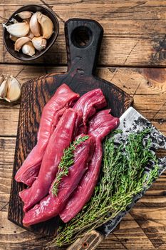 Raw lamb tenderloin Fillet Meat on butcher board with meat cleaver. wooden background. Top view.