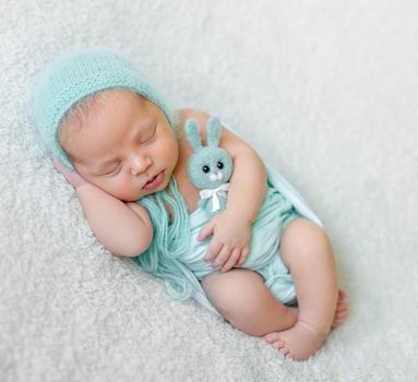 lovely sleeping baby with blue hat, panties and toy on white blanket