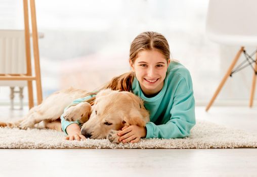 Happy girl lying on floor next to adorable dog indoors