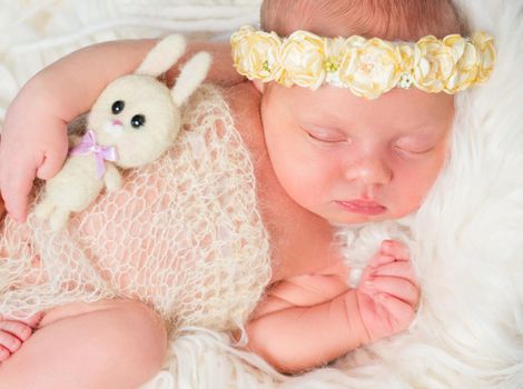 beautiful sleeping newborn girl with little toy and headband with flowers
