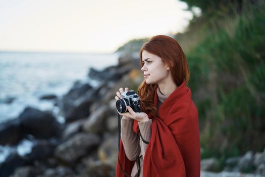 woman hiding with a blanket in nature with a camera vacation photographer travel. High quality photo