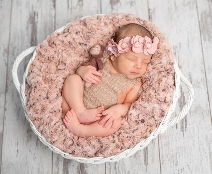 beautiful newborn girl with headband in basket with fluffy blanket