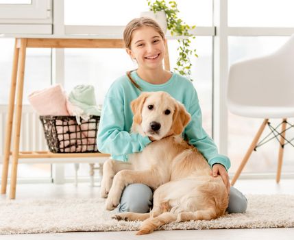 Cheerful girl hugging cute dog in light room