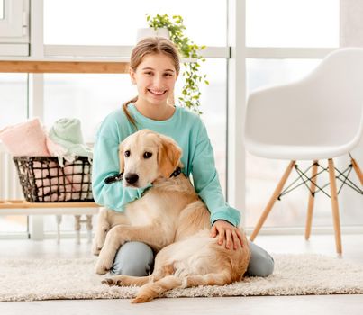 Cheerful girl hugging cute dog in light room