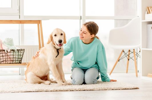 Cheerful teenage girl with sweet golden retriever dog indoors