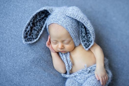lovely newborn boy in blue hare suit with long ears