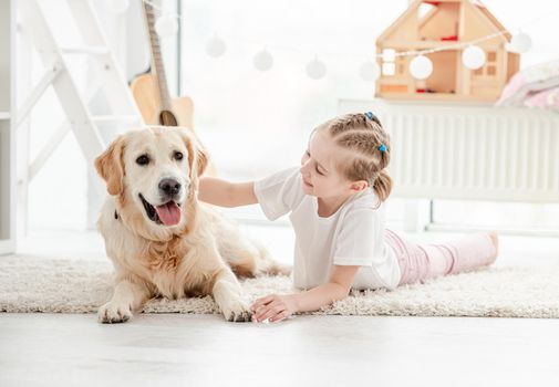 Smiling little girl petting adorable dog in bright room