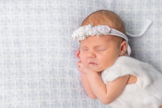 sweet newborn girl sleeping on her hands with flowers on headband