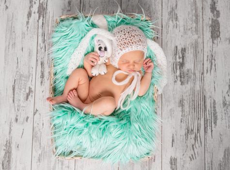 funny sleeping newborn in panties and hat on a cot with turquoise blanket, top view