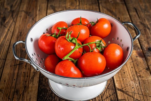 Branch of Red cherry tomatoes in colander. Wooden background. Top view.
