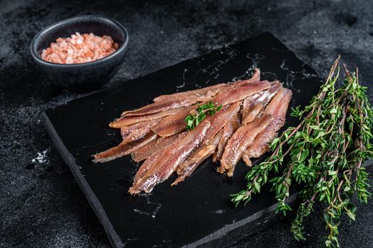 Anchovies fish fillet in Olive Oil. Black background. Top view.