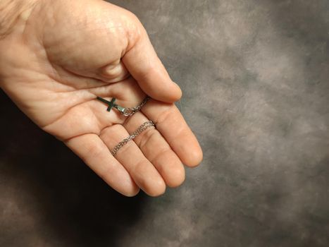 Orthodox silver cross on a chain in a female hand close-up, copy space