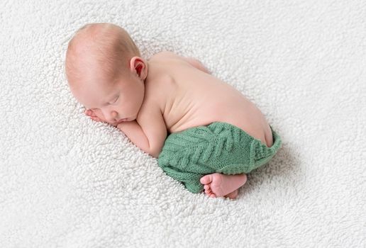 sweet sleeping on ctomach newborn baby on soft white blanket in green panties