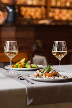 Stuffed mushrooms filled with cheese, mushroom stem and microgreen on the white plate with a glass of wine in the restaurant