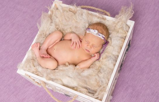 naked sweet baby sleeping in box on violet background, top view