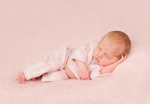 cute sleeping newborn in panties and headband on his head on pink blanket