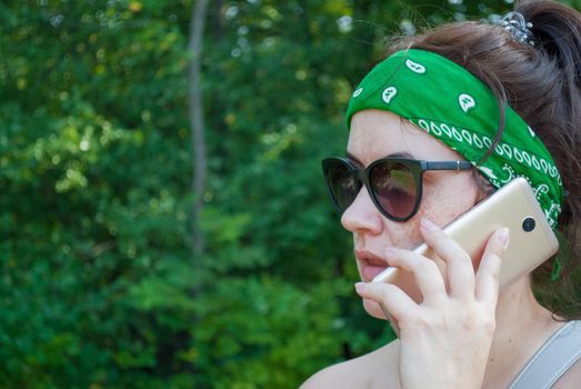 Serious stressed girl speaking on cellphone in park. Frowning young woman in casual calling on mobile phone, listening and staring into distance. Serious phone talk concept.