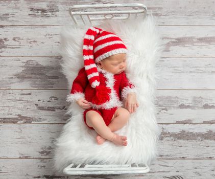 Cute kid in a Christmas costume sleeping in a small bed, topview