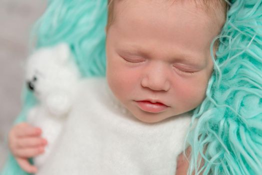 sweet sleeping newborn baby with toy on turquoise fluffy blanket, closeup