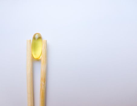 Fish oil capsules with Chinese chopsticks. Omega 3 on a white background. High Resolution Product. Food supplement. Vitamins for a healthy lifestyle. Fatty acid. Metabolism in the body