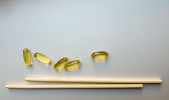 Fish oil capsules with Chinese chopsticks. Omega 3 on a white background. High Resolution Product. Food supplement. Vitamins for a healthy lifestyle. Fatty acid. Metabolism in the body