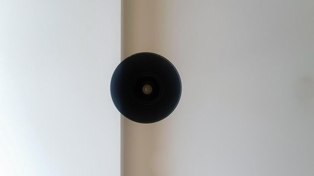 Black round ceiling chandelier or lamp hanging on white from the ceiling. Bottom view of a light bulb. Architectural decoration on the ceiling, hanging round chandelier. Minimalism.