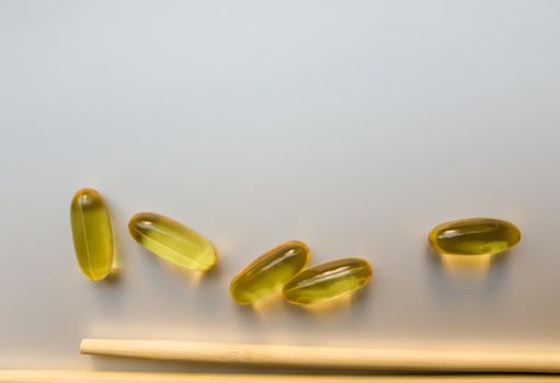 Fish oil capsules with Chinese chopsticks. Omega 3 on a white background. High Resolution Product. Food supplement. Vitamins for a healthy lifestyle. Fatty acid. Metabolism in the body