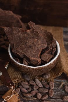 Unsweetened baking block chocolate, cocoa powder, cocoa butter and cocoa beans on old wooden background.