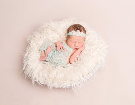 Sweet child girl dressed in lovely pastel suit sleeping on a big soft warm pillow
