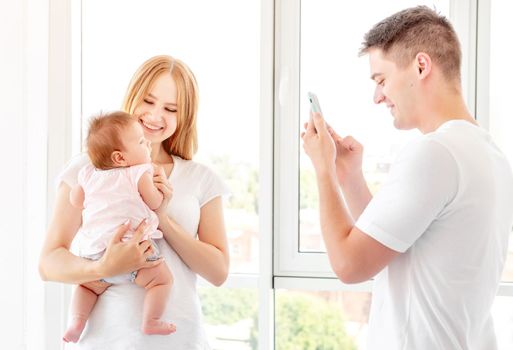 Mother and baby posing for father taking photo indoors